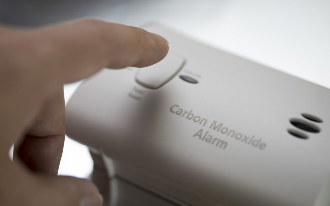 hand pressing the button of a carbon monoxide detector