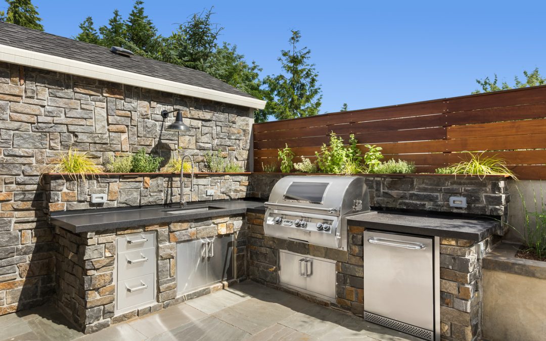 Backyard hardscape patio with outdoor kitchen and barbecue.
