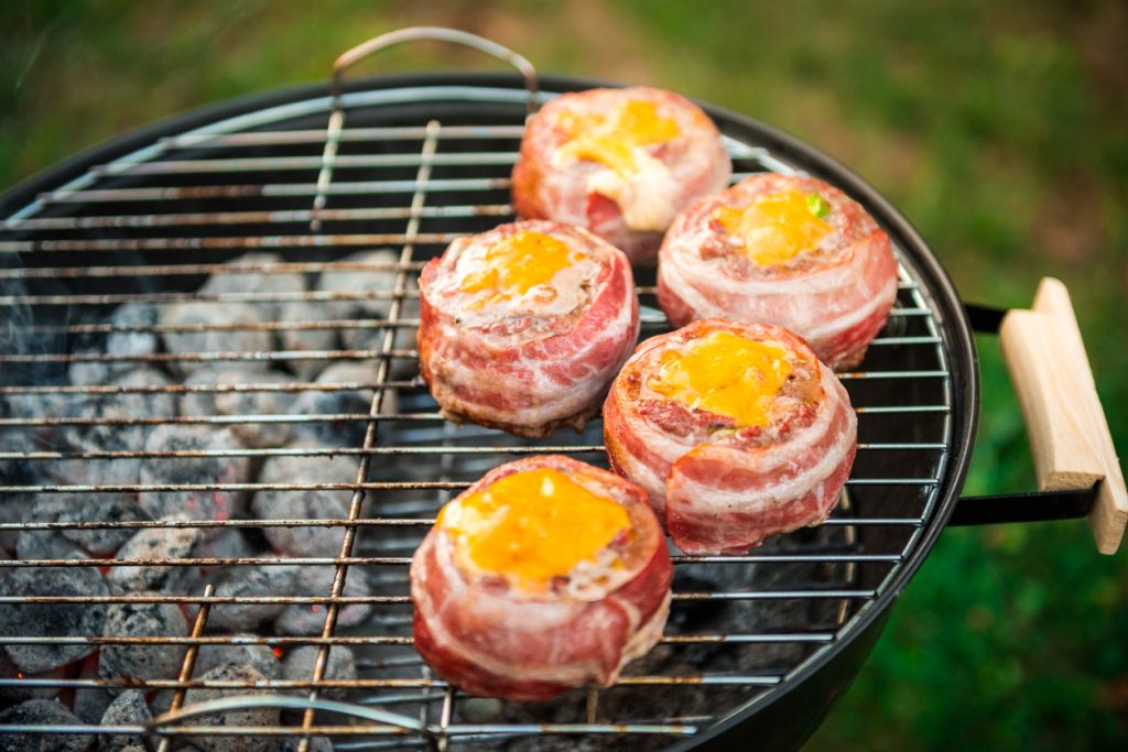 Stuffed patties wrapped in bacon on indirect heat grilling.